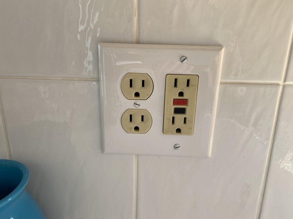 GFCI receptacle in a kitchen with white tile backsplash. Common inspection issues occur when GFCIs are missing or faulty. 