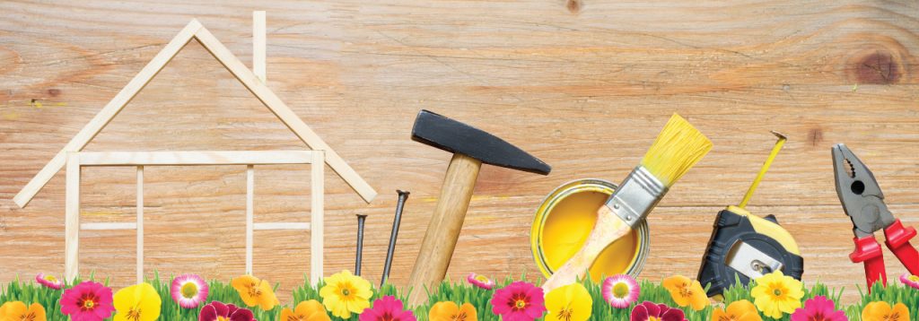 Spring flowers with tools, paint, and a wooden house to depict spring home maintenance projects. 